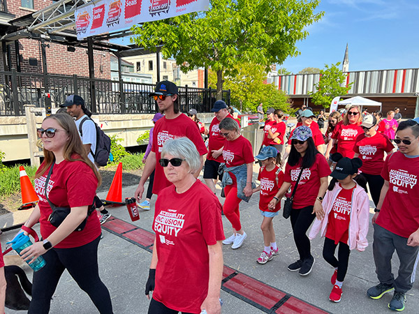 A group of walkers leaves the starting line in red shirts.